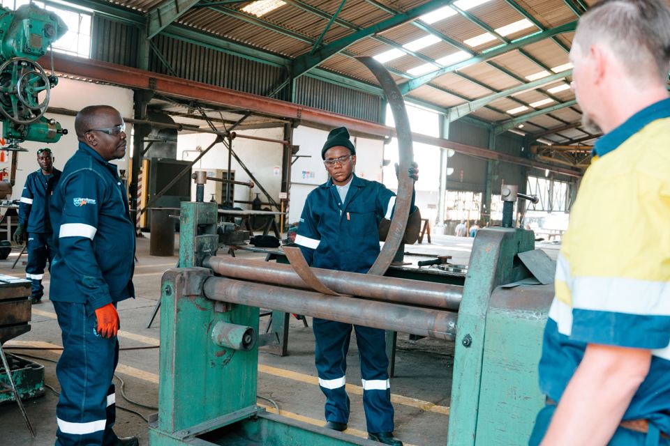 Workshop team rolling a steel plate